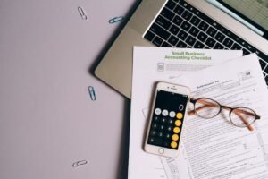 Phone, documents, and laptop on a desk — accounts and subscriptions to cancel after someone dies