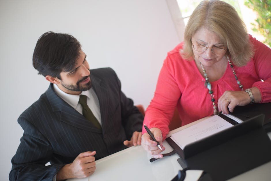 Senior woman reviewing and signing a healthcare directive document with professional assistance
