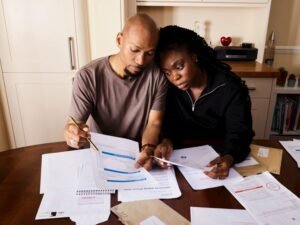 Couple sitting at a table reviewing financial documents and bills — understanding inherited debt after a parent dies