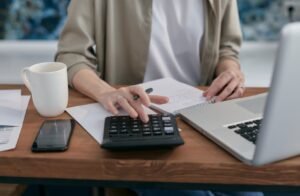 Person organizing digital accounts and taking notes at a desk with laptop — planning their digital estate