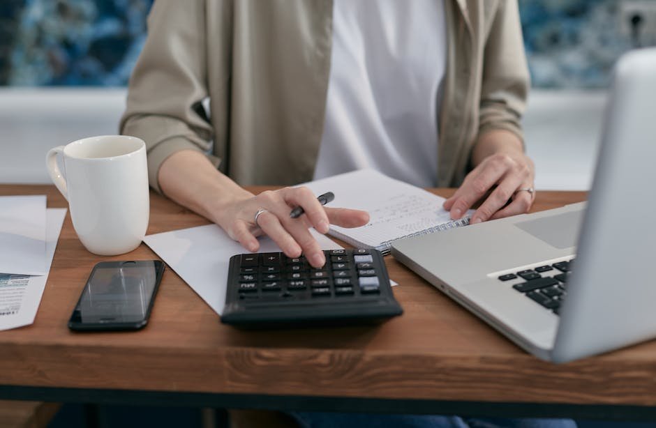 Person organizing digital accounts and taking notes at a desk with laptop — planning their digital estate