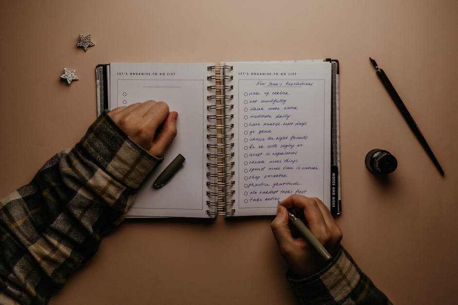 Hands writing in a notebook at a wooden desk — filling out an emergency information worksheet for family