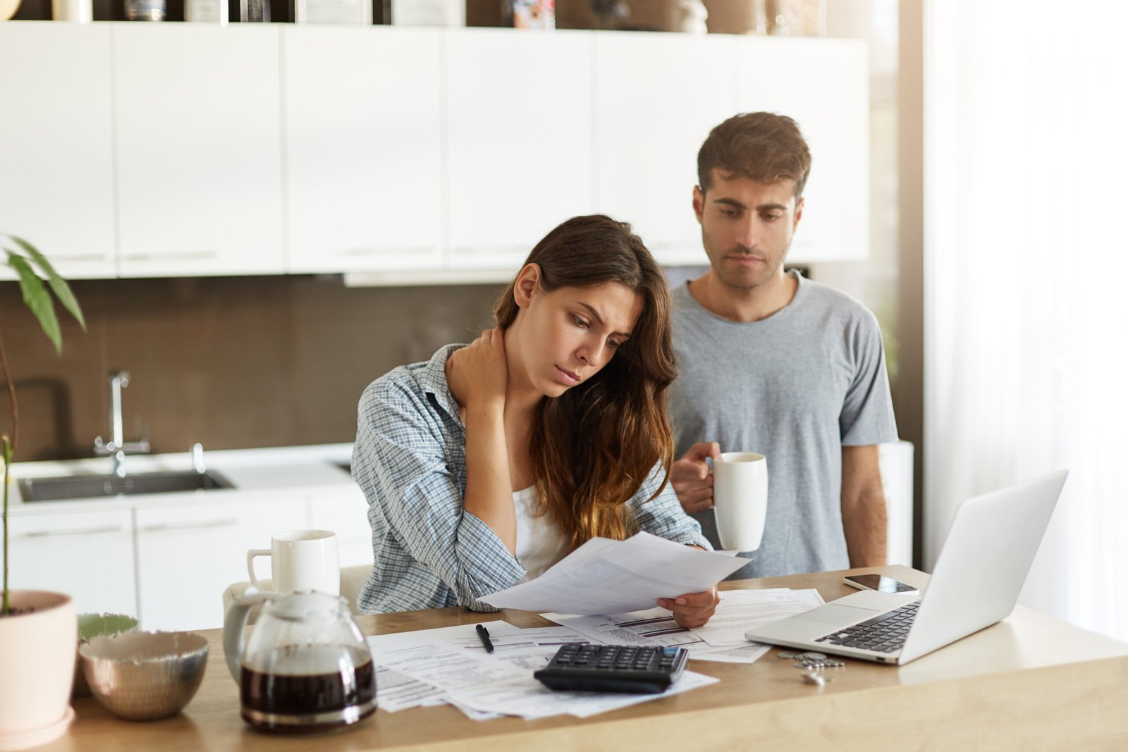 A couple at their kitchen table overwhelmed by bills and paperwork