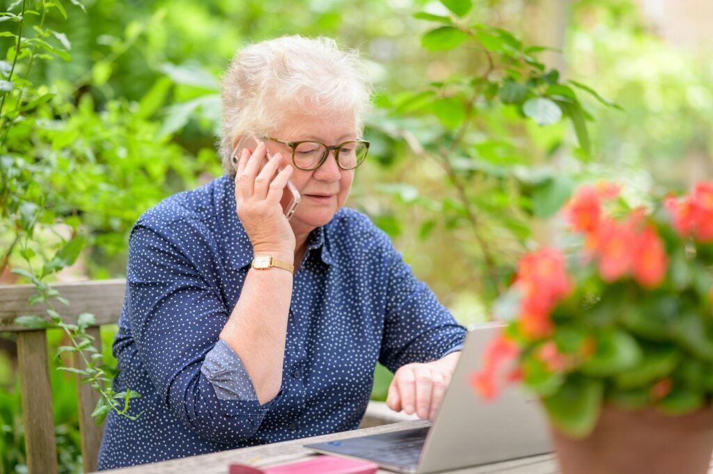 Elderly woman sitting with a laptop, representing a parent with dementia whose passwords and digital accounts need to be organized