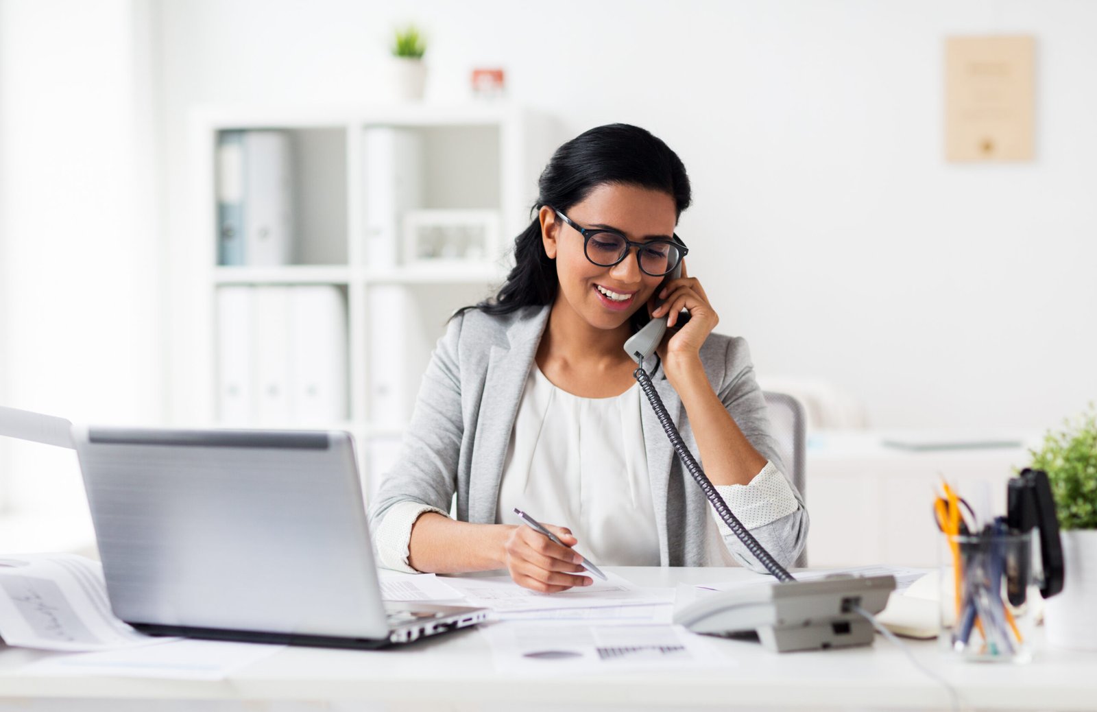 An Aftercare Specialist on a call, taking notes at her desk